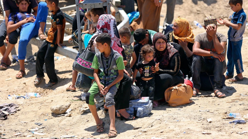 Displaced Iraqis from Ramadi rest before crossing the Bzebiz bridge after spending the night walking towards Baghdad, as they flee their hometown on May 16, 2015. (Photo by Hadi Mizban/AP)