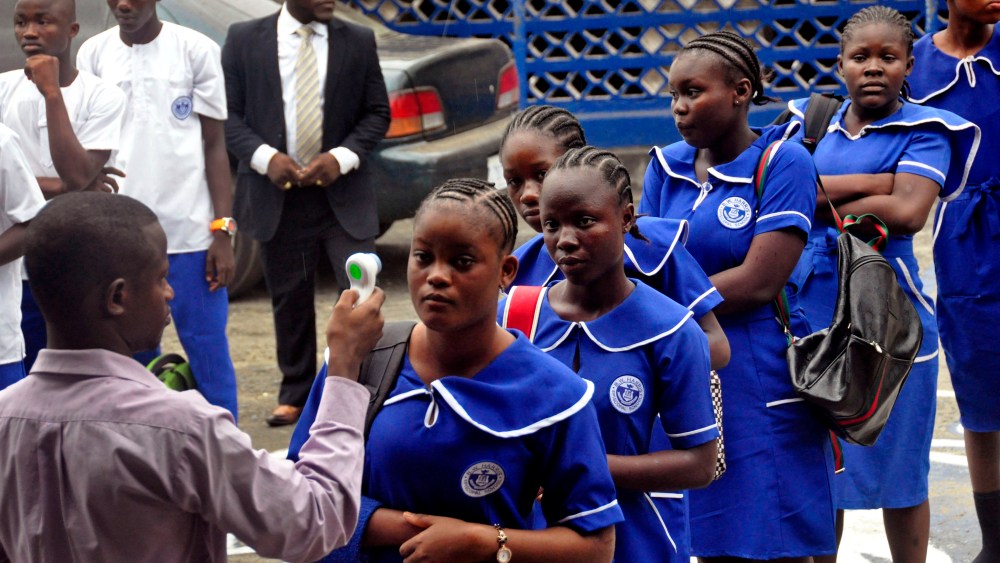 A Liberian school teacher takes the temperature of students as they arrive for morning lessons at school, as part of the Ebola prevention measures put in place at the BW Harris High School in Monrovia, Liberia, Feb. 16, 2015. (Photo by Abbas Dulleh/AP)