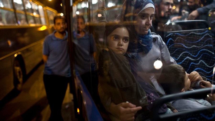 A woman and her children sit as they have boarded a bus provided by Hungarian authorities for migrants and refugees at Keleti train station in Budapest, Hungary, Sep. 5, 2015. (Photo by Marko Drobnjakovic/AP)