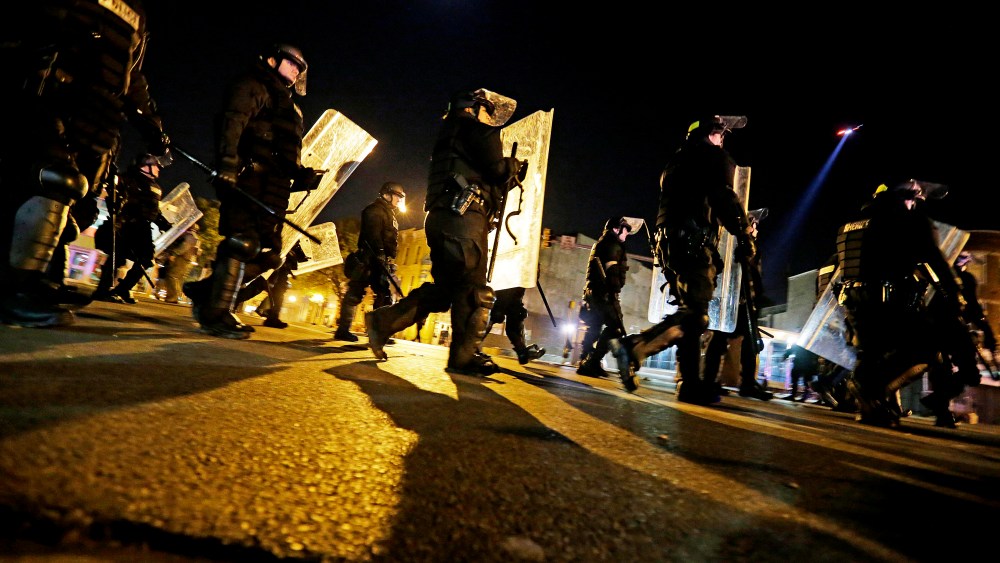 Police in riot gear return to a staging area after lining up to enforce a curfew imposed in the aftermath of rioting following Monday's funeral for Freddie Gray, who died in police custody, May 1, 2015, in Baltimore. (Photo by David Goldman/AP)