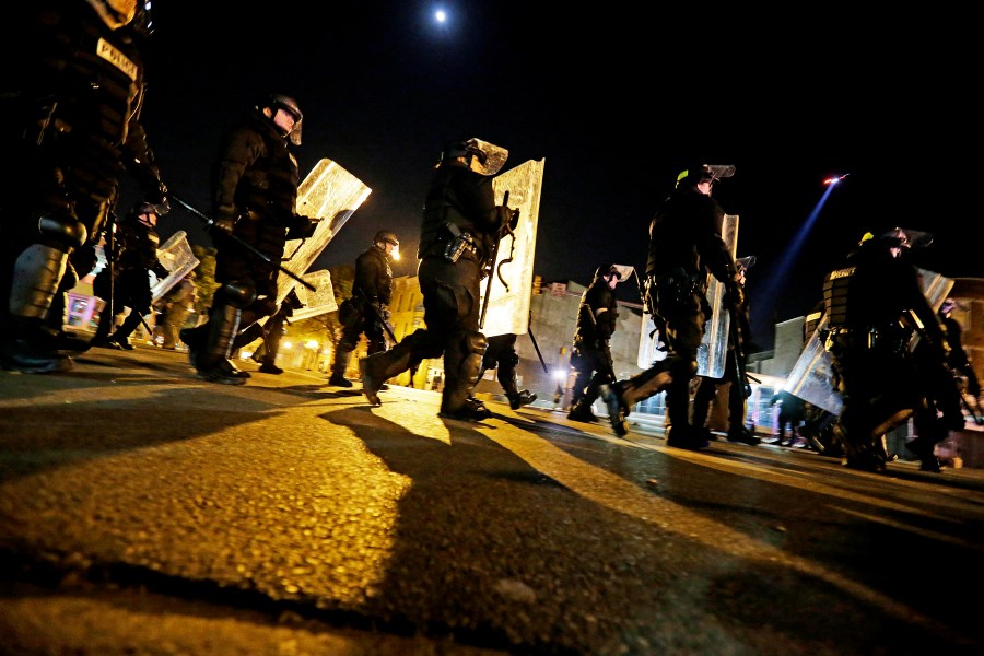 Police in riot gear return to a staging area after lining up to enforce a curfew imposed in the aftermath of rioting following Monday's funeral for Freddie Gray, who died in police custody, May 1, 2015, in Baltimore. (Photo by David Goldman/AP)