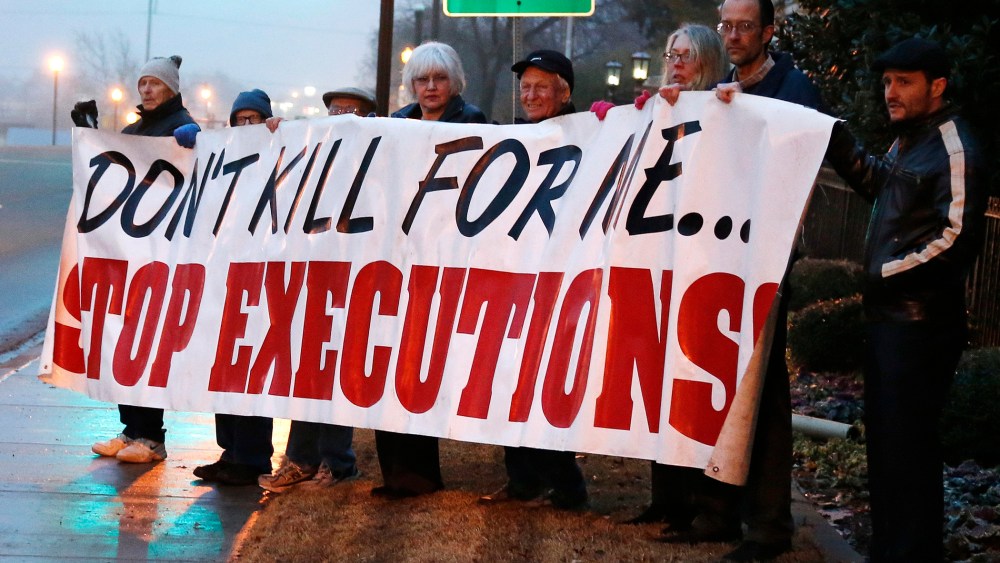 Death penalty opponents hold a sign outside the Governor's mansion in Oklahoma City, Jan. 9, 2014.