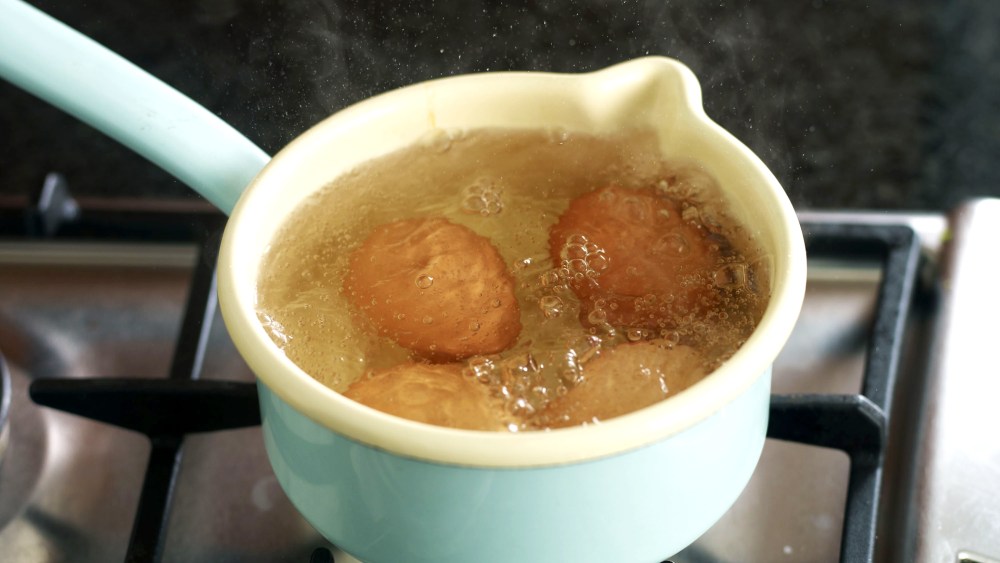 Eggs boiling in small saucepan.
