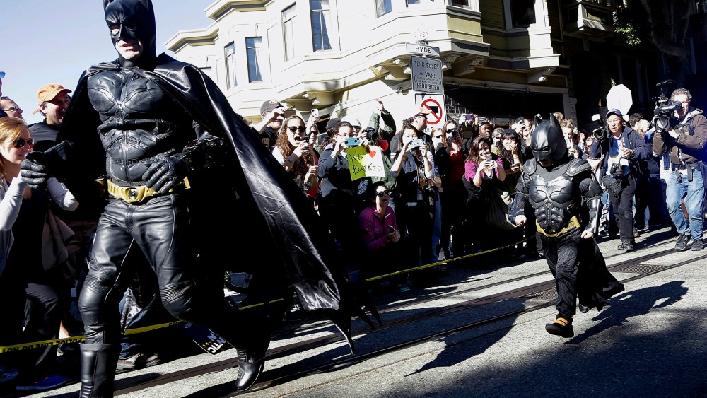 Miles Scott, dressed as Batkid, right, runs with Batman after saving a damsel in distress in San Francisco, Nov. 15, 2013.