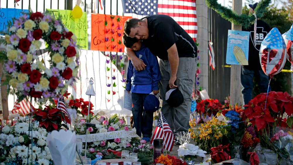 Gary Mendoza, and his son Michael pay their respects at a makeshift memorial site honoring shooting victims, in San Bernardino, Calif. (Photo by Jae C. Hong, File/AP)
