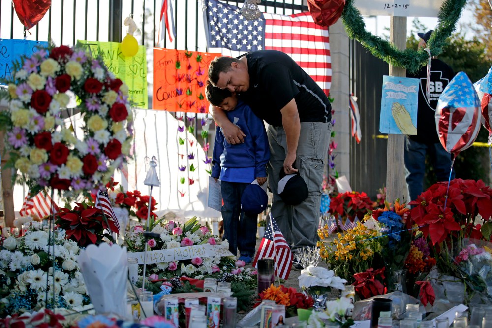 Gary Mendoza, and his son Michael pay their respects at a makeshift memorial site honoring shooting victims, in San Bernardino, Calif. (Photo by Jae C. Hong, File/AP)