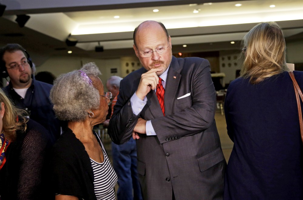 Republican mayoral hopeful Joe Lhota, center, receives instructions from a poll worker at his polling station during the primary election in New York, Tuesday, Sept. 10, 2013.