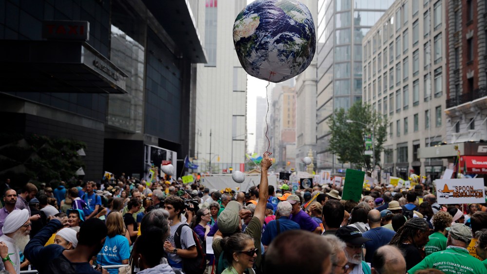 A man throws an earth balloon into the air as people fill 58th Street between 8th and 9th Avenue before a global warming march in New York Sunday, Sept. 21, 2014. (Photo by Mel Evans/AP)