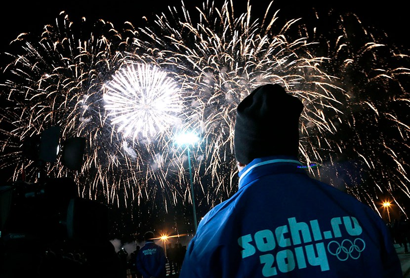 A volunteer watches fireworks during a ceremony to mark a 1 year to the start of 2014 Winter Olympics, in Sochi, Russia, on Thursday, Feb. 7, 2013. (Photo by Ivan Sekretarev/AP)