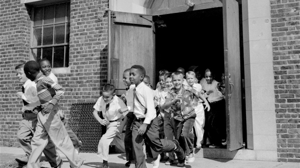 Black and white fourth graders at St. Martin School, Washington, DC, dash for the playground at recess, September 17, 1954.