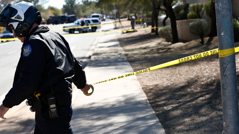 A Phoenix Police Department officer puts up police tape near a crime scene on Jan. 30, 2013. (Photo by Ross Franklin/AP)