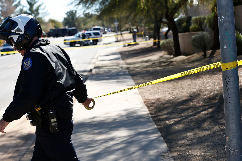 A Phoenix Police Department officer puts up police tape near a crime scene on Jan. 30, 2013. (Photo by Ross Franklin/AP)
