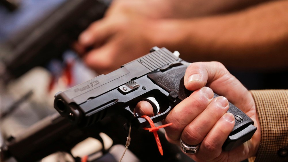 A convention attendee handles a .45 caliber semiautomatic pistol at a trade show on Jan. 15, 2013, in Las Vegas, Nev. (Photo by Julie Jacobson/AP)