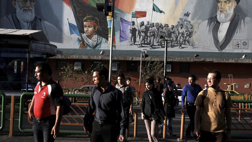 Pedestrians walk past a poster in Tehran depicting Iranian soldiers during the war with Iraq in the 1980s, on Sept. 25, 2013.