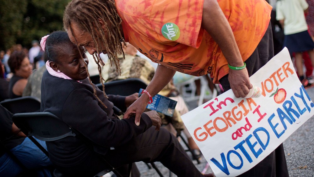 Alvin Dollar, of Decatur, right, carries a sign proclaiming he voted early as he talks with Dianna Green, of Atlanta at a Democratic rally encouraging early voting before U.S. Senate candidate Michelle Nunn takes the stage, on Oct. 27, 2014, in Decatur.