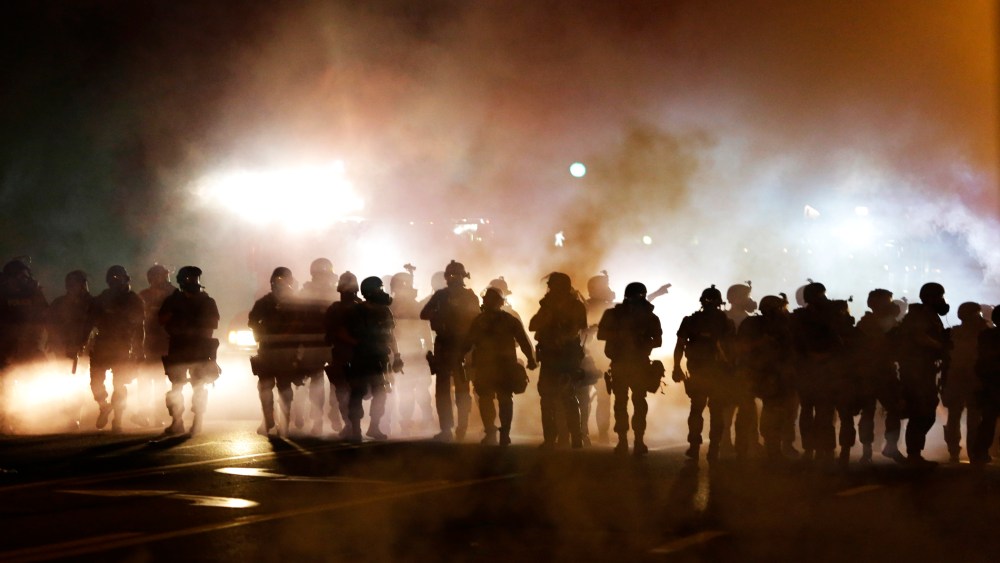 Police advance through smoke, Wednesday, Aug. 13, 2014, in Ferguson, Mo.