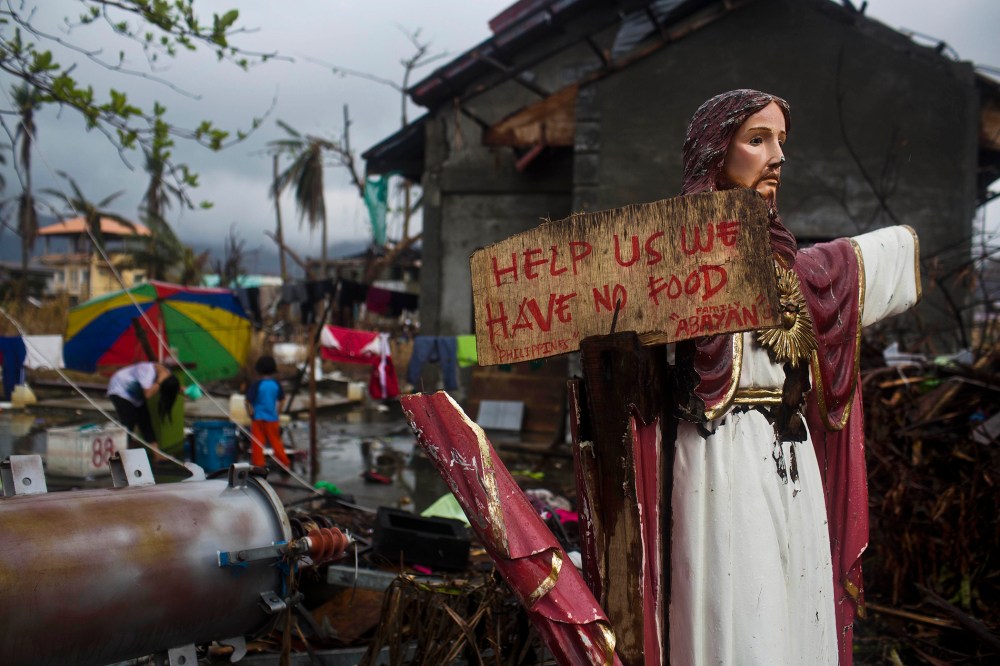 A plea for help painted on a sign hangs from a damaged statue of Jesus in a Typhoon Haiyan destroyed neighborhood in Tacloban, Philippines on Nov. 22, 2013.