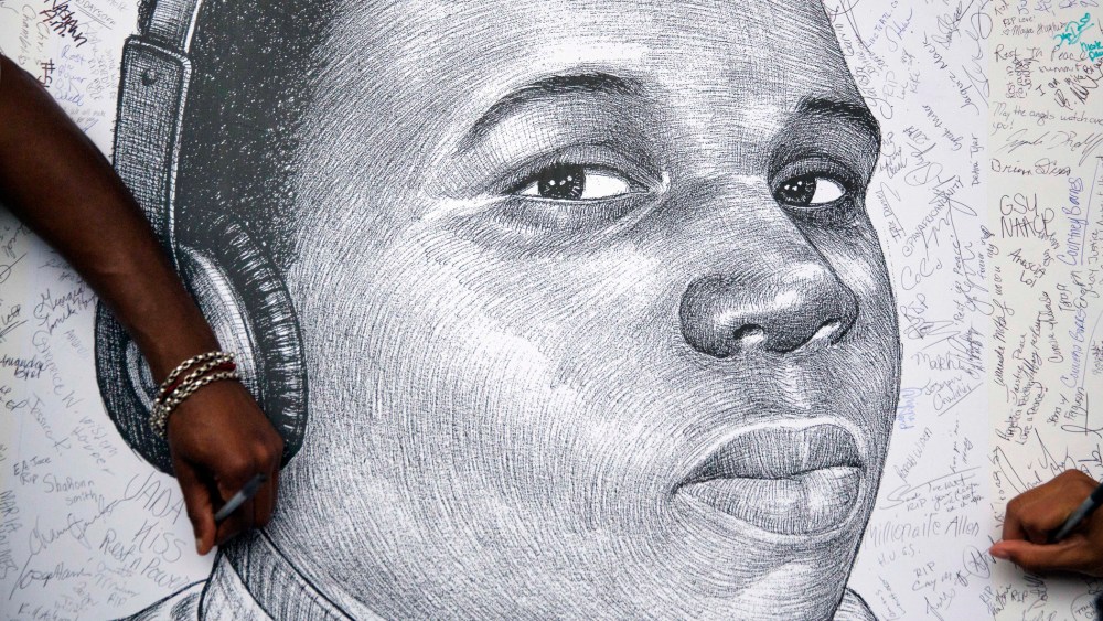 Protestors autograph a sketch of Michael Brown during a protest, Monday, Aug. 18, 2014, in Atlanta, Ga. (Photo by David Goldman/AP)