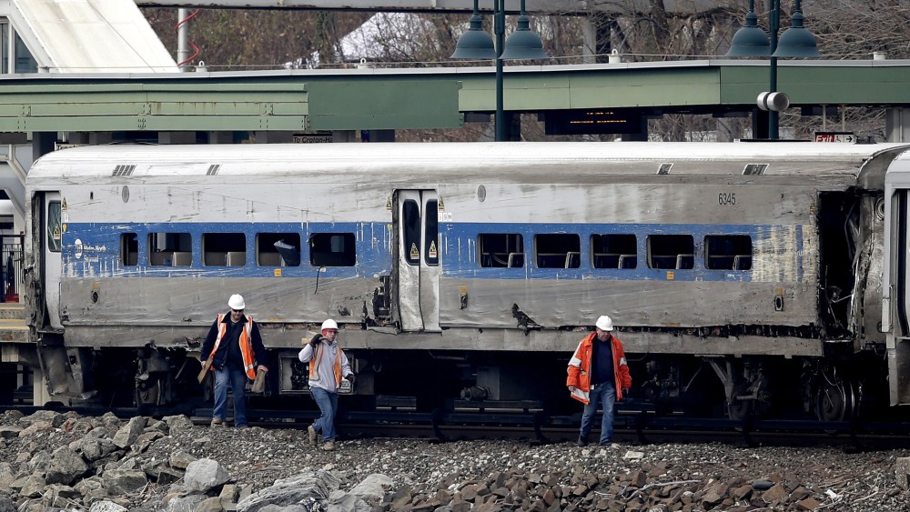 Workers walk past a Metro-North train car that was damaged in a derailment in the Bronx section of New York, Dec. 2, 2013.