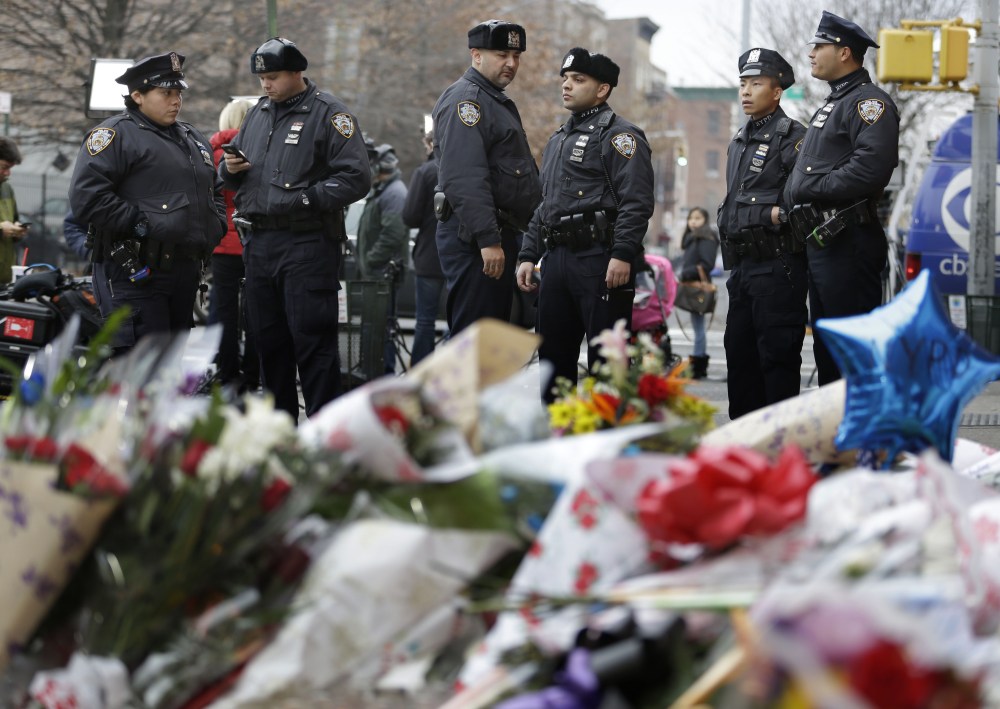 New York City police officers gather near a makeshift memorial near the site where fellow officers Rafael Ramos and Wenjian Liu were murdered in the Brooklyn borough of New York, Dec. 22, 2014.