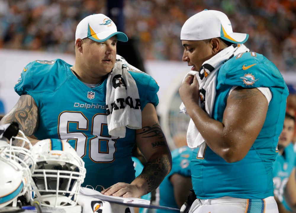 Miami Dolphins guard Richie Incognito (68) and tackle Jonathan Martin (71) looks over plays during the second half of an NFL preseason football game against the Tampa Bay Buccaneers, Saturday, Aug. 24, 2013 in Miami Gardens, Fla.