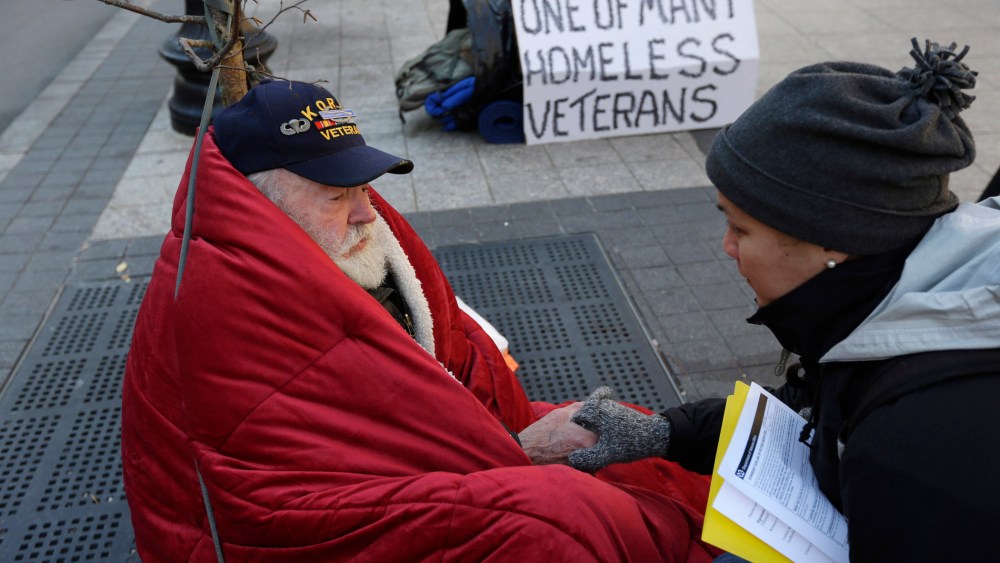 Homeless Korean War veteran Thomas Moore, 79, left, speaks with Boston Health Care for the Homeless street team outreach coordinator Romeena Lee on a sidewalk in Boston, Nov. 20, 2013.