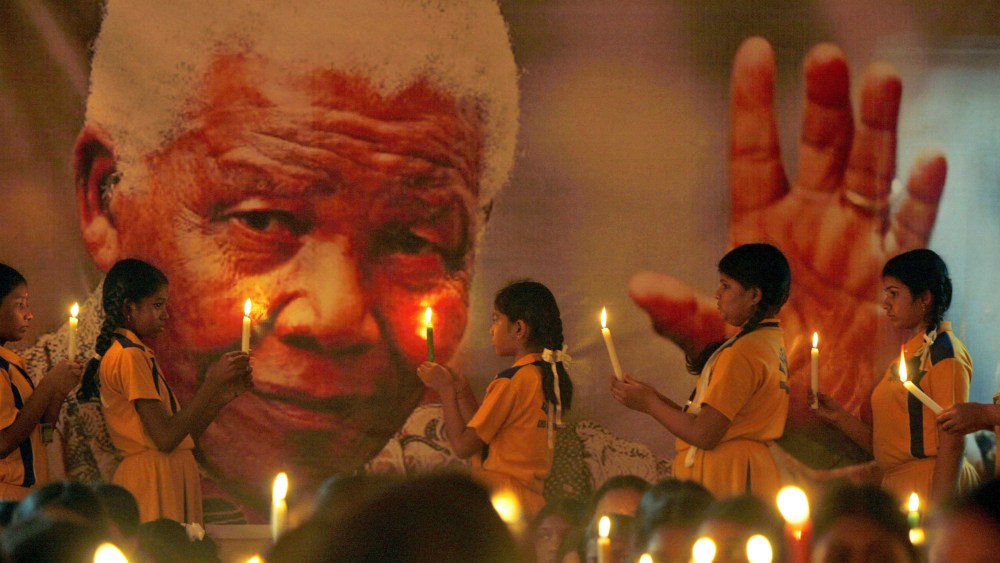 Schoolchildren hold candles near a giant portrait of former South African President Nelson Mandela in Chennai, India, Dec. 6, 2013.