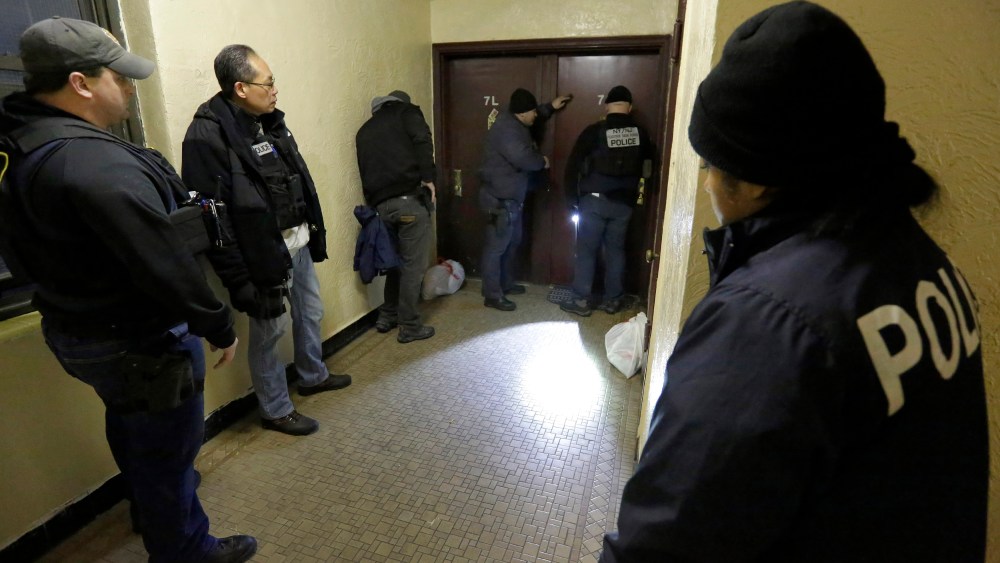 Immigration and Customs Enforcement officers try to gain entry to an apartment, in the Bronx borough of New York, during a series of early-morning arrests, March 3, 2015. (Photo by Richard Drew/AP)