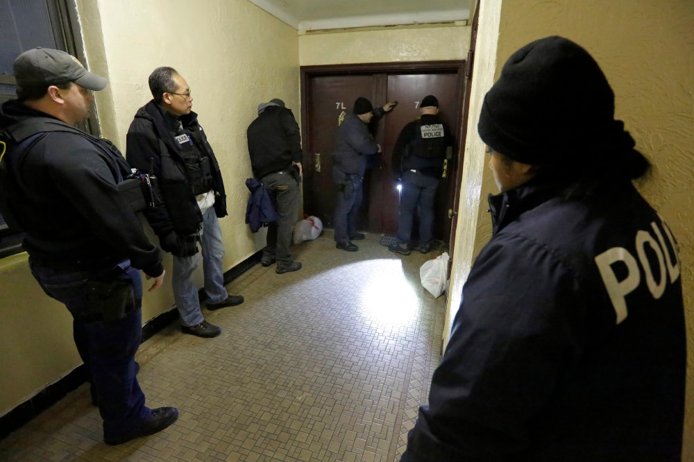 Immigration and Customs Enforcement officers try to gain entry to an apartment, in the Bronx borough of New York, during a series of early-morning arrests, March 3, 2015. (Photo by Richard Drew/AP)