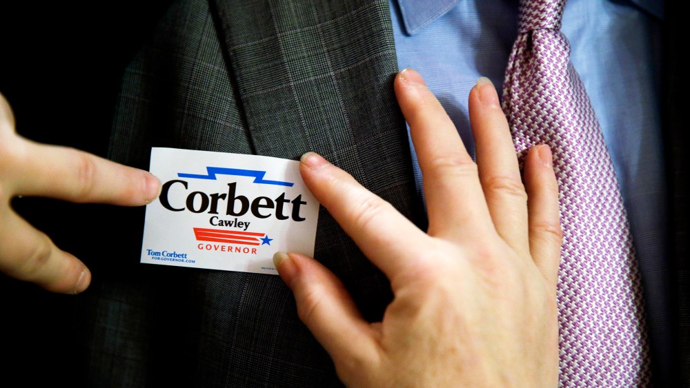 A supporter of Pennsylvania Gov. Tom Corbett places a campaign sticker, Nov. 7, 2013.