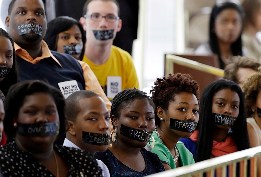 Members of North Carolina student chapters of the NAACP  and opponents of voter ID legislation wear tape over their mouths while sitting silently in the gallery of the House chamber of the North Carolina General Assembly where lawmakers debated and...