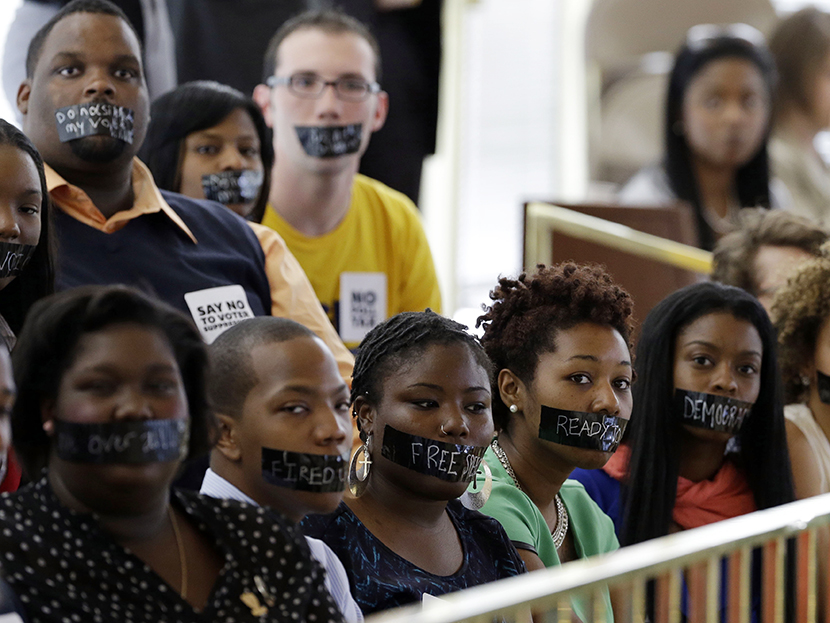 Members of North Carolina student chapters of the NAACP  and opponents of voter ID legislation wear tape over their mouths while sitting silently in the gallery of the House chamber of the North Carolina General Assembly where lawmakers debated and...