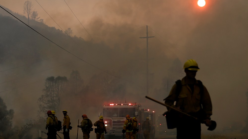 Firefighters walk under smoke from fires along Morgan Valley Road near Lower Lake, Calif., July 31, 2015. A series of wildfires were intensified by dry vegetation, triple-digit temperatures and gusting winds. (Photo by Jeff Chiu/AP)