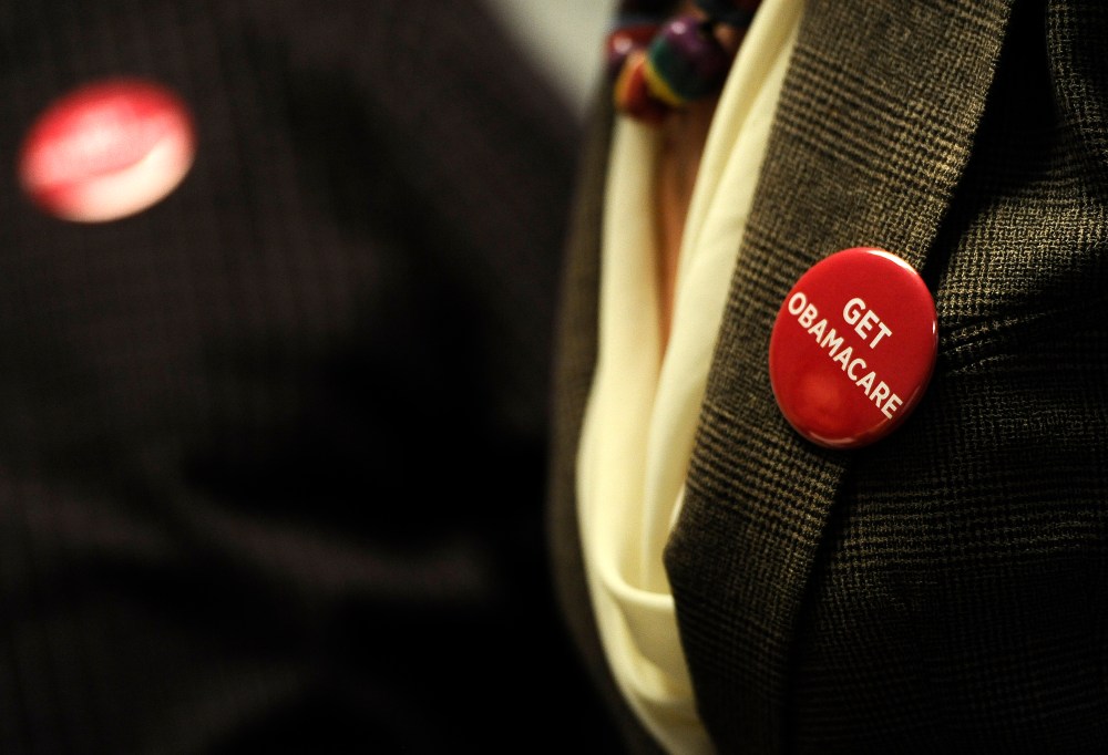 Associates at Community Health Center wear buttons during a session to enroll people in the nation's new health insurance system Oct. 1, 2013, in New Britain, Conn.