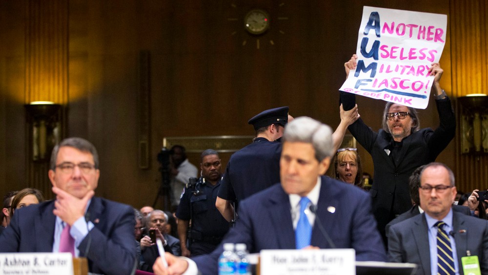 A CodePink demonstrator is escorted out by a member of the Capitol Police on Capitol Hill in Washington, D.C., March 11, 2015. (Photo by Pablo Martinez Monsivais/AP)