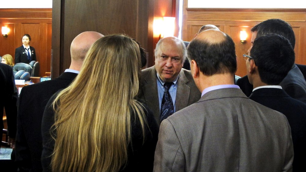 Max Gruenberg, D-Anchorage, huddles with fellow minority Democrats during a break in the floor debate on a minimum wage bill in Juneau, Alaska, April 13, 2014.