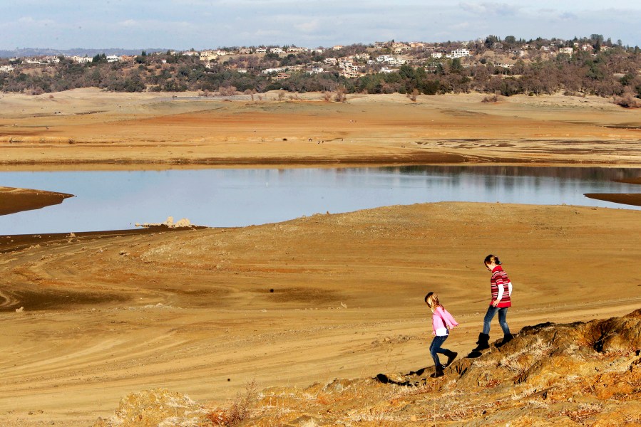 With the edge of Folsom Lake, Calif., more than 100 yards away, Gina, 8, left, and Sydney, 9, Gerety walk on rocks that are usually at the waters edge, Jan. 9, 2014.
