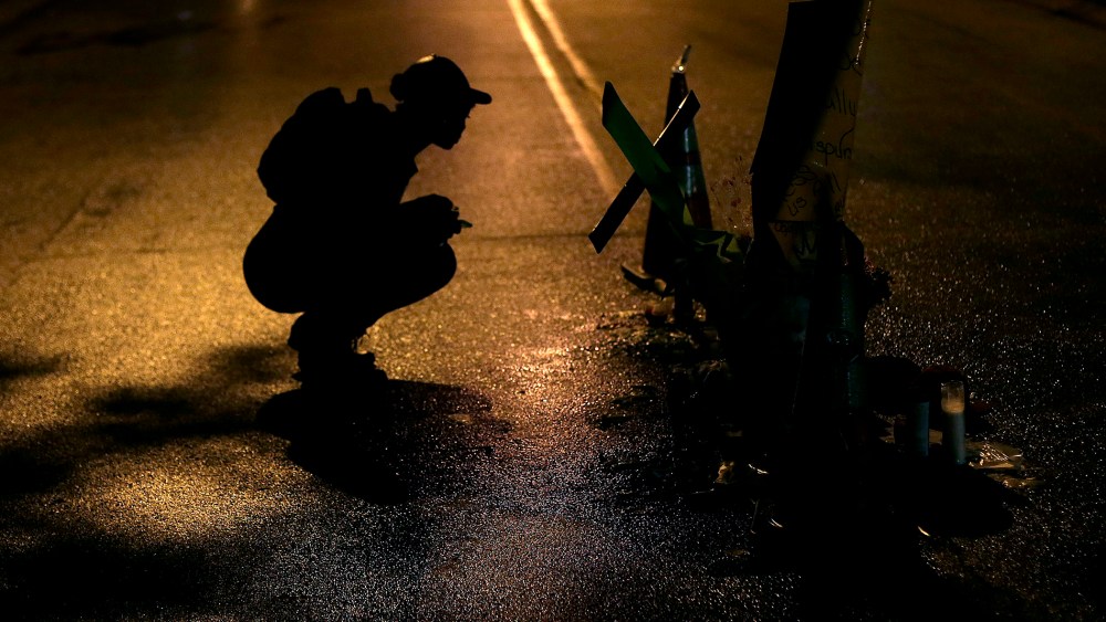 A woman pauses, Aug. 15, 2014, before a makeshift memorial in the middle of the street where Michael Brown was killed by police Aug. 9 in Ferguson, Mo.