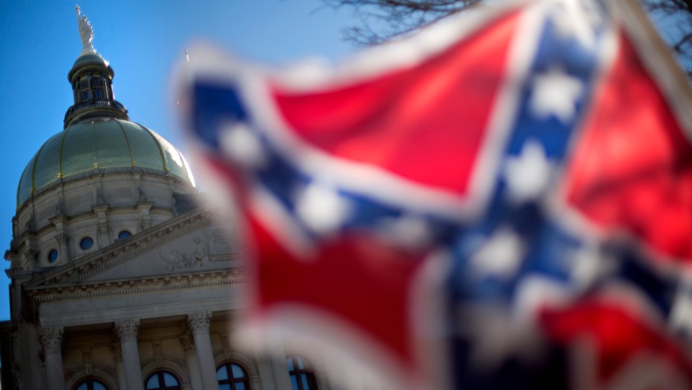 The dome of the State Capitol is seen as a protestor waves a Confederate flag during the March For Life anti-abortion rally, Jan. 22, 2014, in Atlanta, Ga. (Photo by David Goldman/AP)