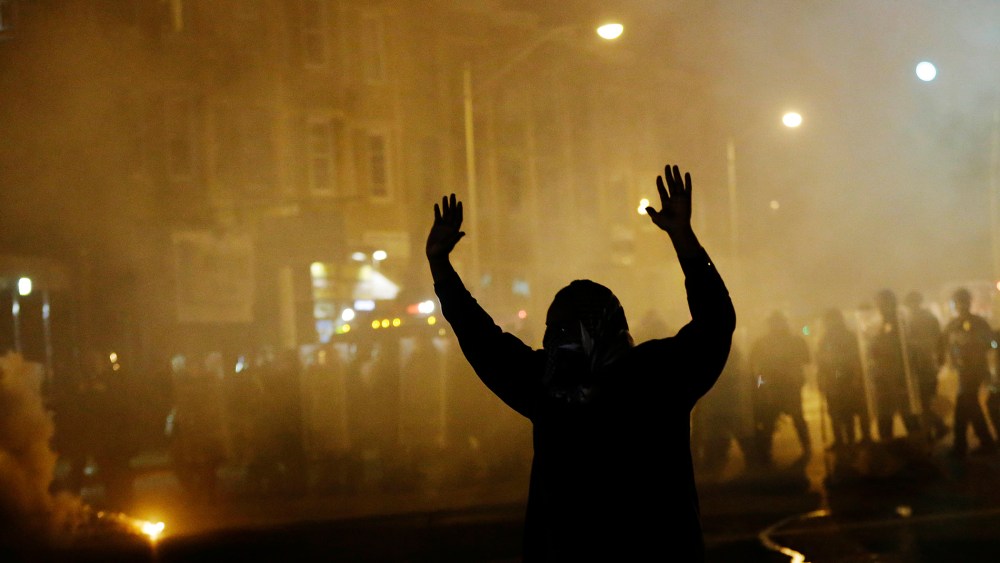 A protestor walks away as police in riot gear advance on the crowd after a 10 p.m. curfew went into effect in the wake of Monday's riots following the funeral for Freddie Gray, April 28, 2015, in Baltimore. (Photo by David Goldman/AP)