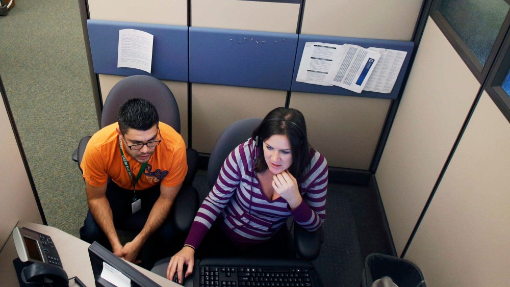 MNsure insurance exchange representatives Carlos Villanueva, left, and Emily Joyce prepare for the Oct. 1 open enrollment debut at the center in St. Paul, Minnesota.