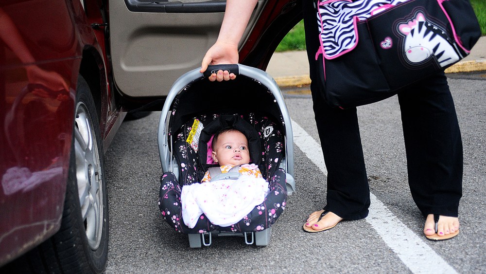 18 year-old mother Kasiyah Buckner lifts her daughter into her car outside of St. Paul Lutheran in St. Joseph, Mo., May 9, 2013.