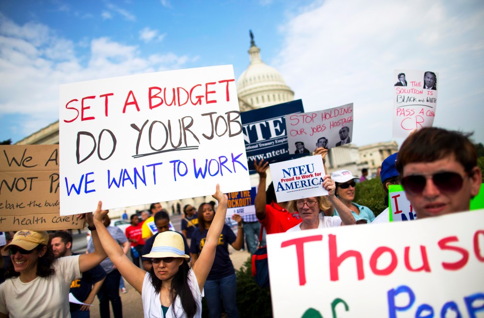 Protestors hold signs during a during an event with the Democratic Progressive Caucus and furloughed federal employees on Capitol Hill in Washington, Friday, Oct. 4, 2013.