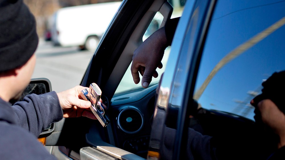 A police officer collects a gun from from a motorist during a gun buyback, in Atlanta, Georgia, Jan. 16, 2014.