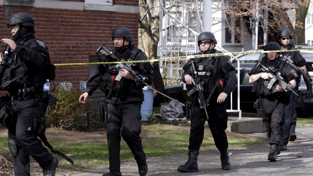 Officials wearing tactical gear search an apartment building in Watertown, Mass., Friday, April 19, 2013.  Two suspects in the Boston Marathon bombing killed an MIT police officer, injured a transit officer in a firefight and threw explosive devices at...