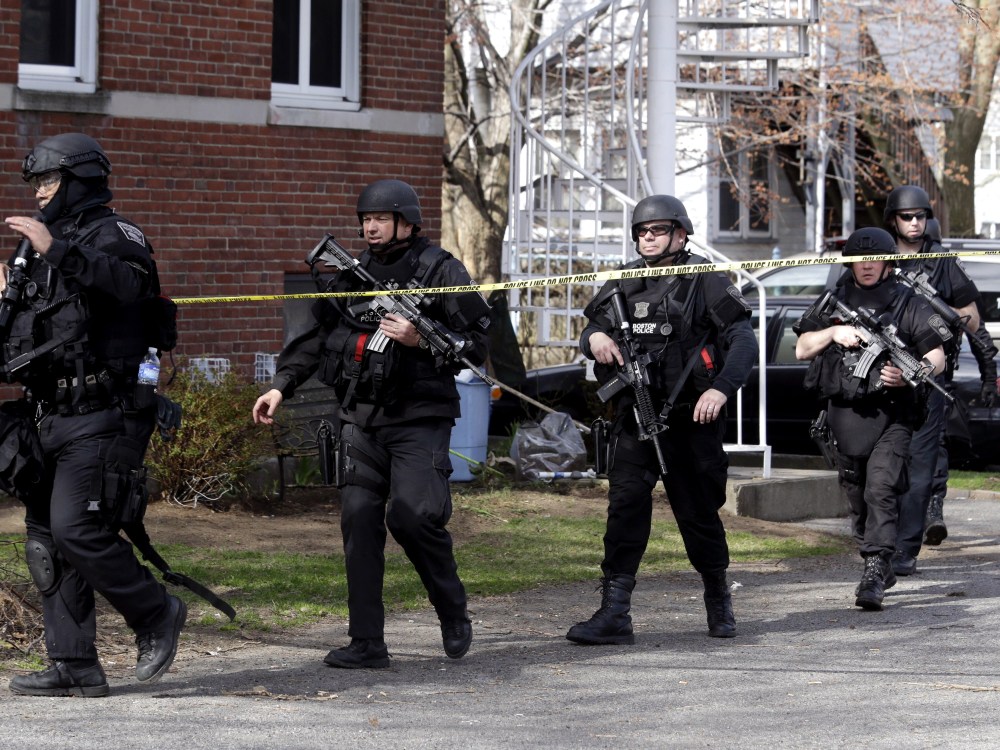 Officials wearing tactical gear search an apartment building in Watertown, Mass., Friday, April 19, 2013. Two suspects in the Boston Marathon bombing killed an MIT police officer, injured a transit officer in a firefight and threw explosive devices at...