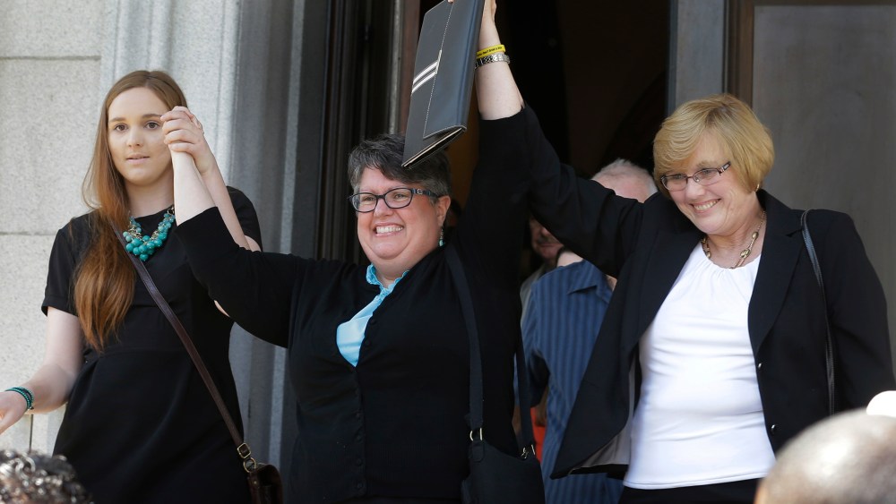 Plantiffs in the federal suit over Virginia's ban on gay marriage, Emily Schall-Townley, left, Carol Schall, center, and Mary Townley, raise their arms after a hearing on Virginia's same sex-marriage ban in Richmond, Va., on May 13, 2014.