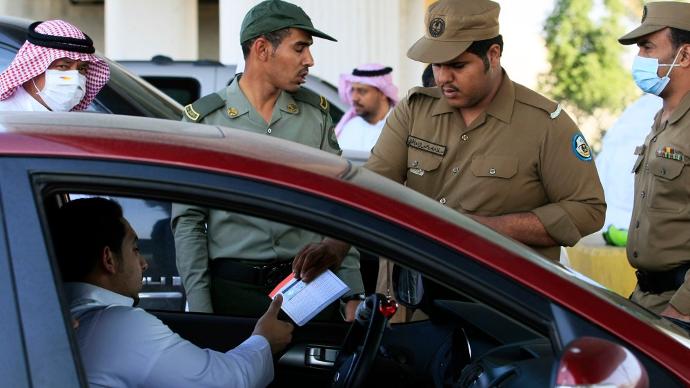 In this file photo taken Friday, Nov. 12, 2010, a Saudi policeman checks identity papers of pilgrims at a checkpoint outside Mecca, Saudi Arabia.