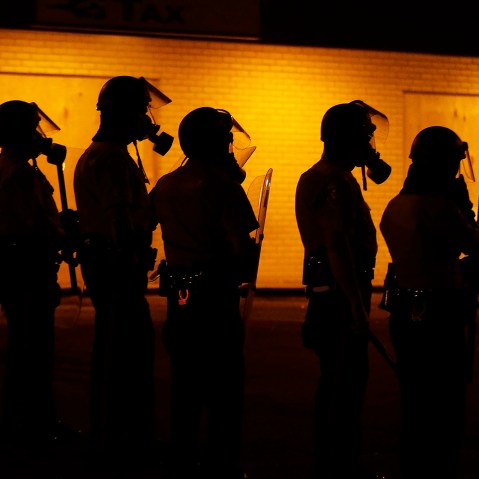 Police wait to advance after tear gas was used to disperse a crowd, Aug. 17, 2014, in Ferguson, Mo.