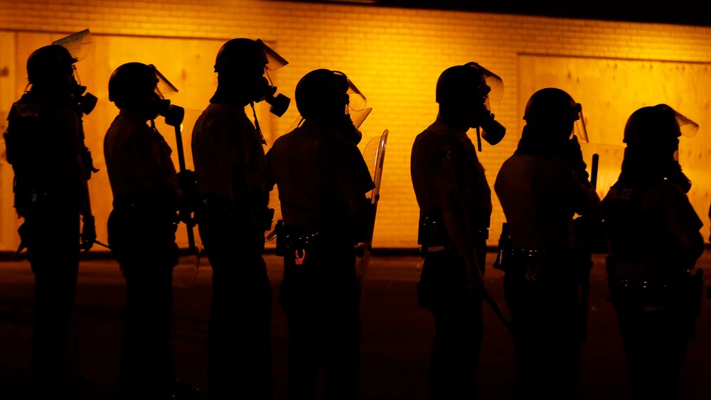Police wait to advance after tear gas was used to disperse a crowd, Aug. 17, 2014, in Ferguson, Mo.